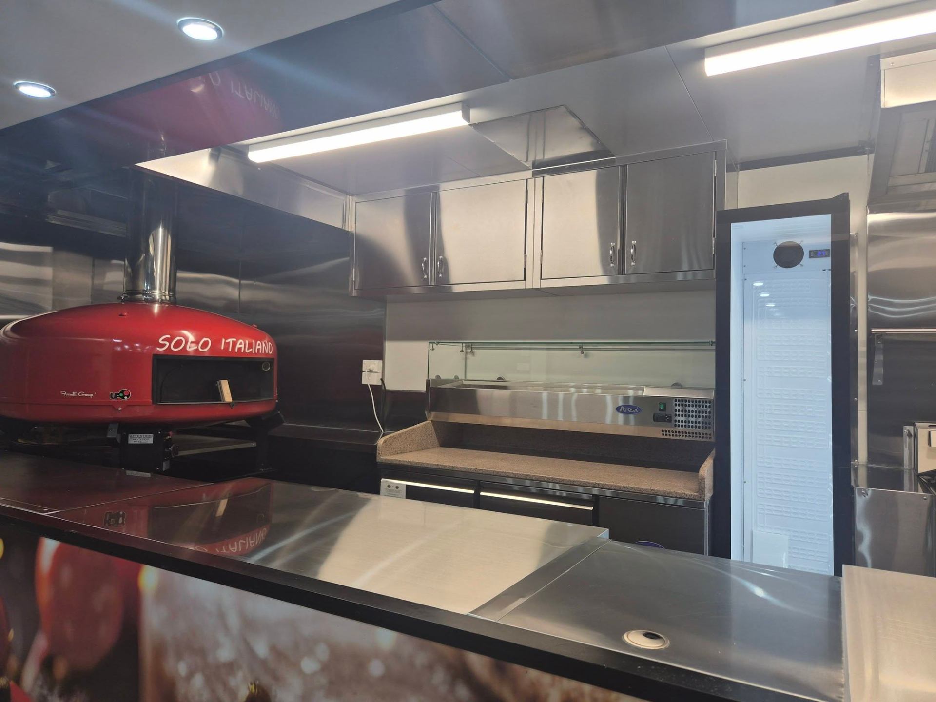 Solo Italiano interior fit out inside a Custom Food Vans build with red wood fired pizza oven and stainless cabinets