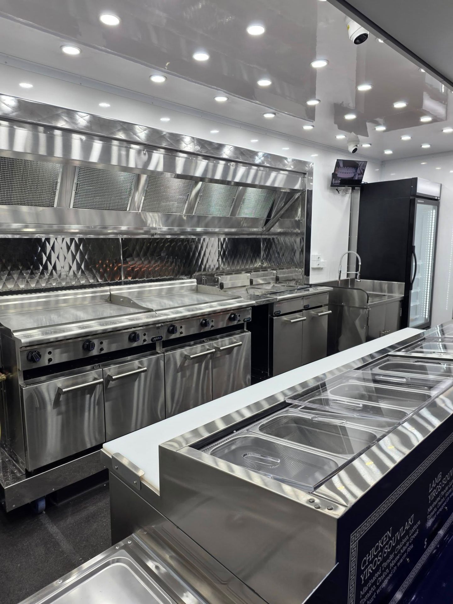 Stainless steel commercial kitchen fit out inside a Custom Food Vans build with flat top grills, extraction canopy and bain marie